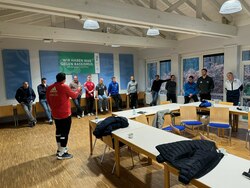 Eine Gruppe mit Seminarteilnehmern steht vor einem Plakat mit dem Titel wir haben was gegen Rassismus und tauscht sich mit einem Referenten aus