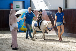 Ein Mädchen beim geführten Reiten auf einem Pony