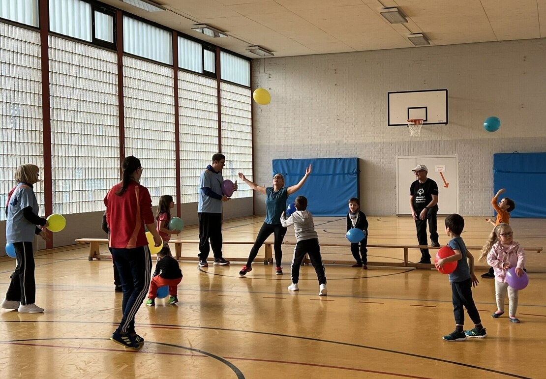 Grundschulkinder spielen in der Turnhalle mit Luftballons