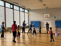 Grundschulkinder spielen in der Turnhalle mit Luftballons