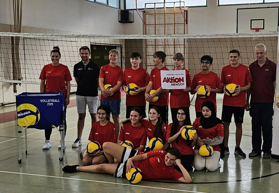 Gruppenfoto eines Volleyballteams mit einem Plakat von Aktion Mensch