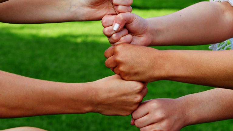 Sechs Fäuste werden mit ausgestrecktem Arm übereinander gehalten