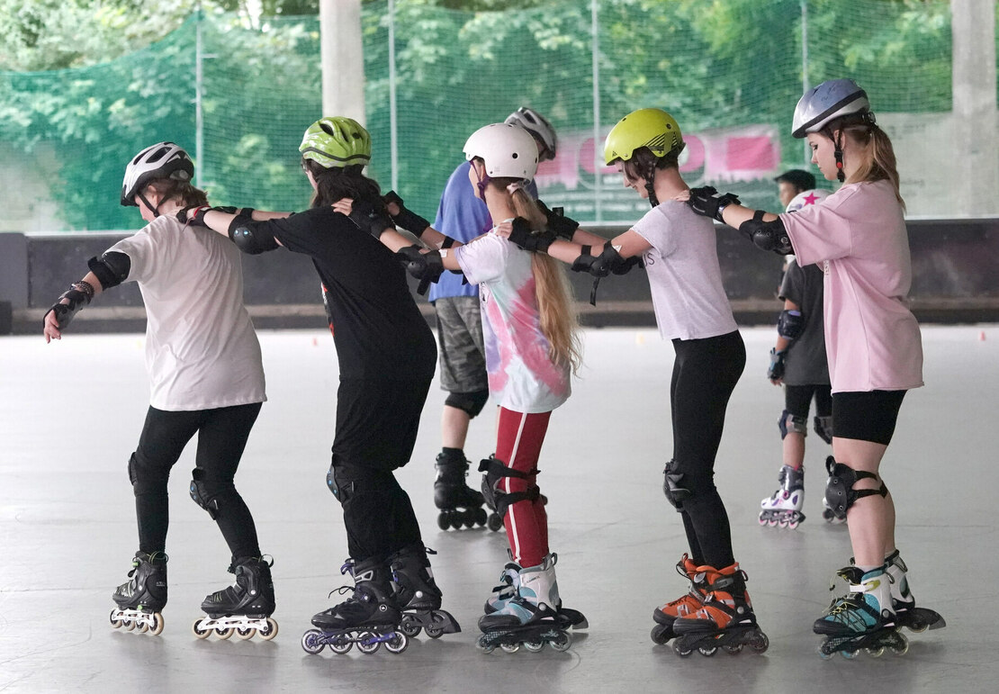Fünf Mädchen fahren hintereinander in einer Reihe Inline Skate