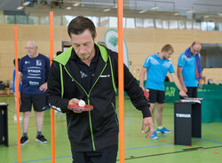 TW220158.jpg Ein Sportler balanciert einen Tischtennisball auf einem Tischtennisschläger durch einen Parkour